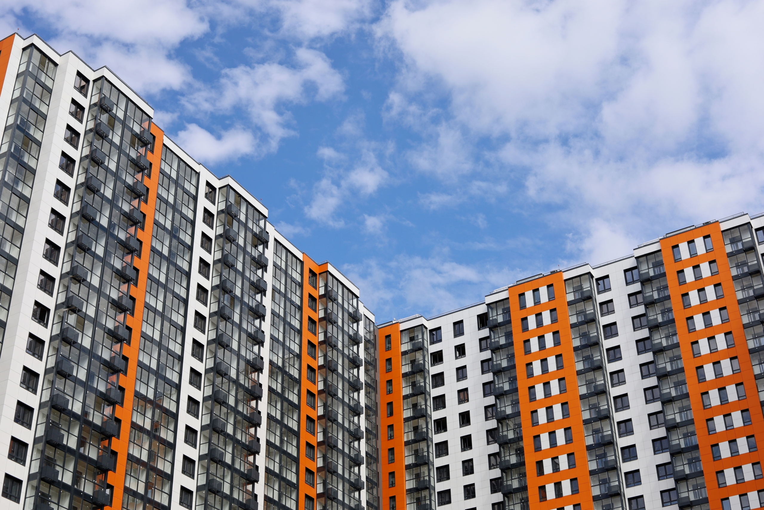 New,Residential,Building,With,Orange,And,White,Cladding,Against,Blue